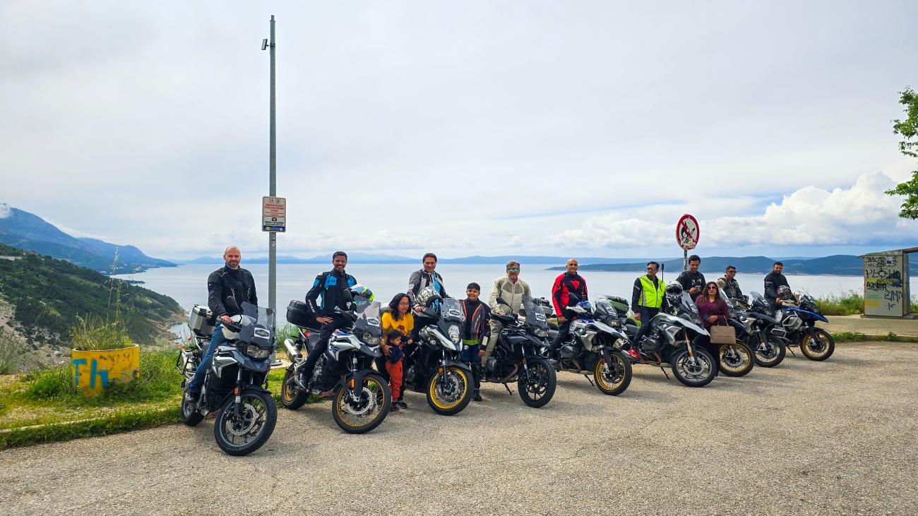 MotoRover tour group lined up with their motorcycles at a coastal viewpoint overlooking the Adriatic Sea.