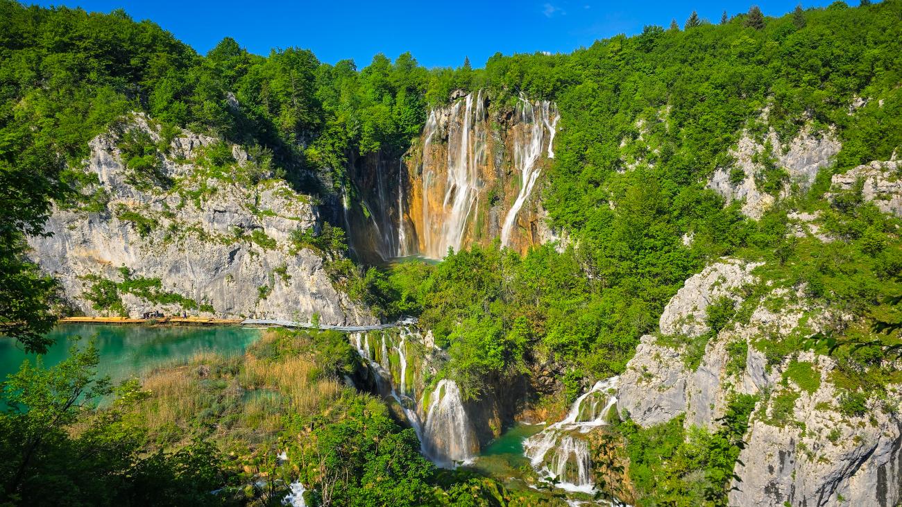 Cascading waterfalls surrounded by lush forest at Plitvice Lakes National Park in Croatia.