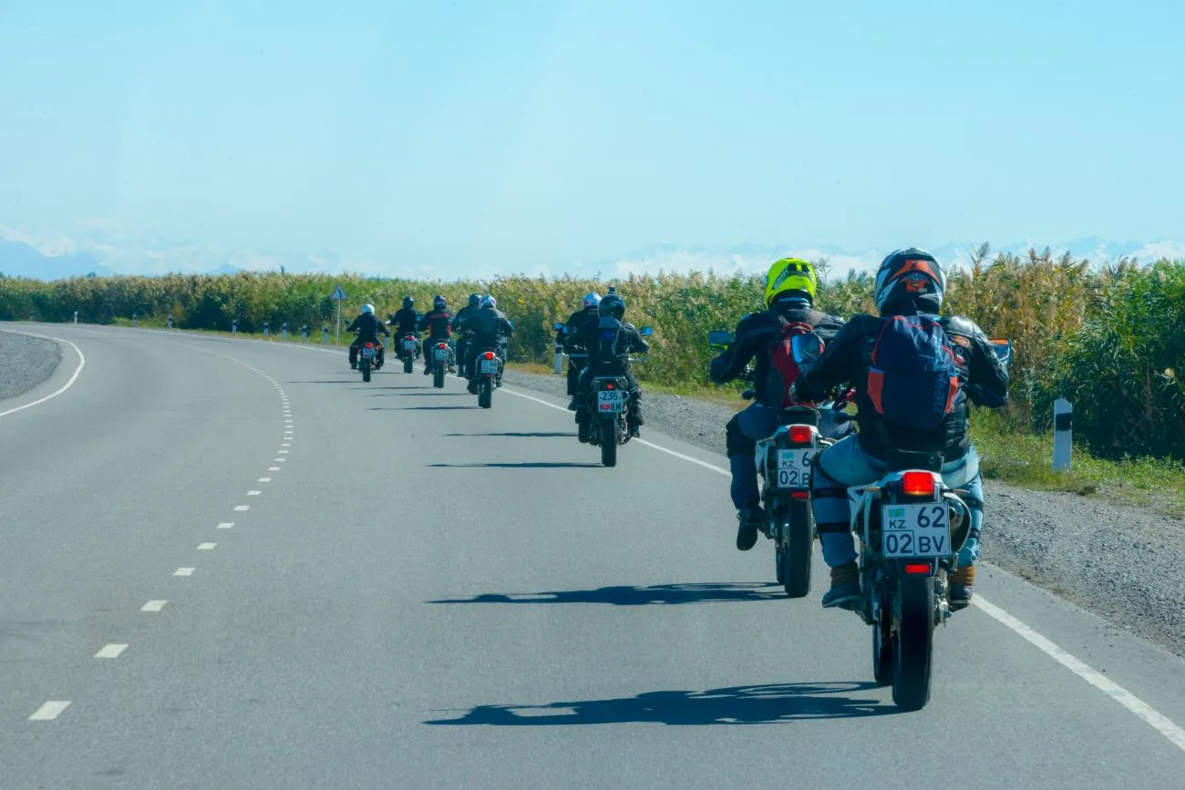 Group of riders on an open mountain road in Kyrgyzstan with distant mountains
