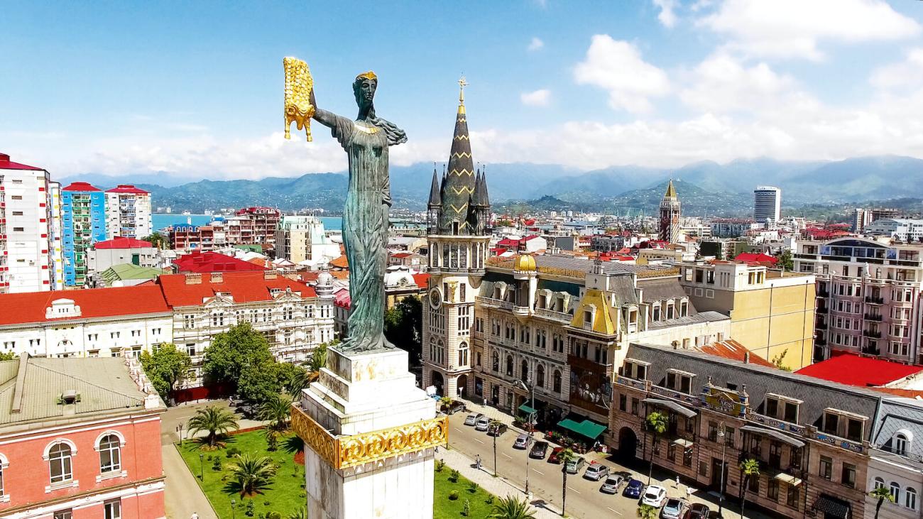 The golden Medea statue holding the Golden Fleece towers over Batumi city square with the Black Sea coast and mountains behind