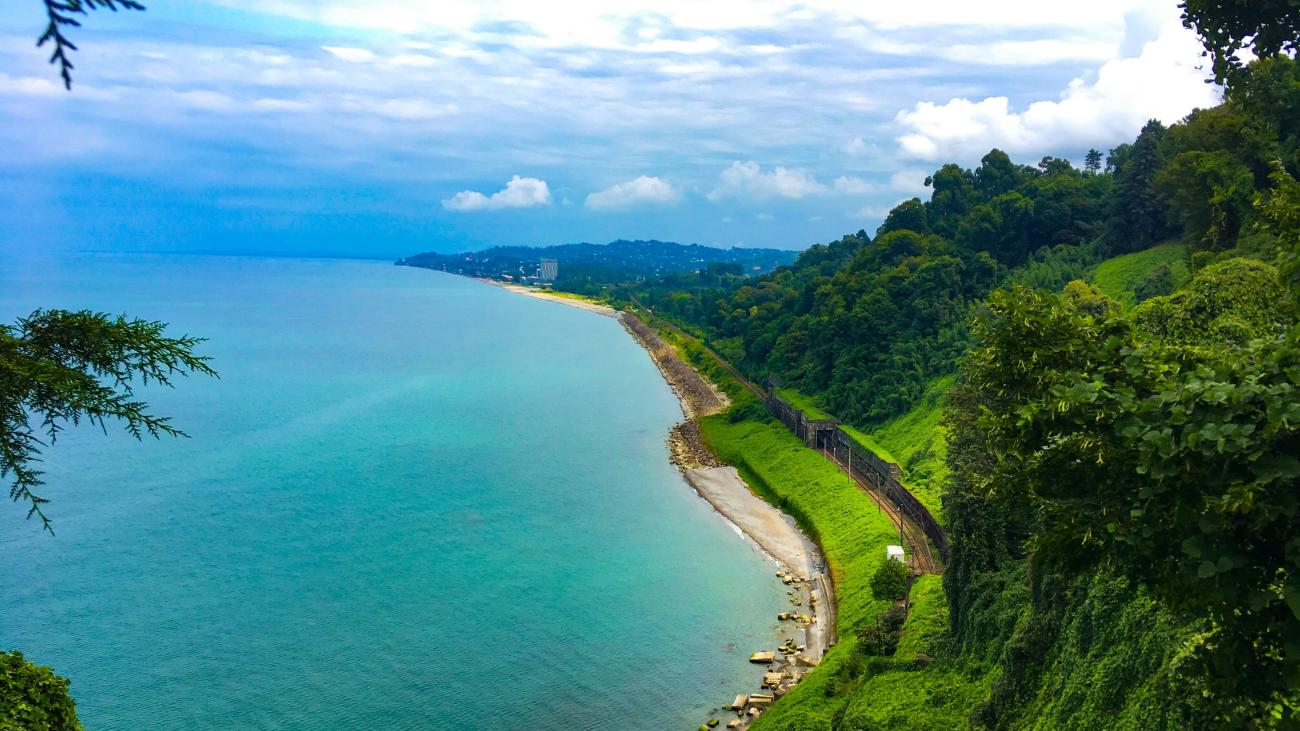 A panoramic view of the turquoise Black Sea coastline near Batumi with lush green hills and a curved shoreline stretching into the distance