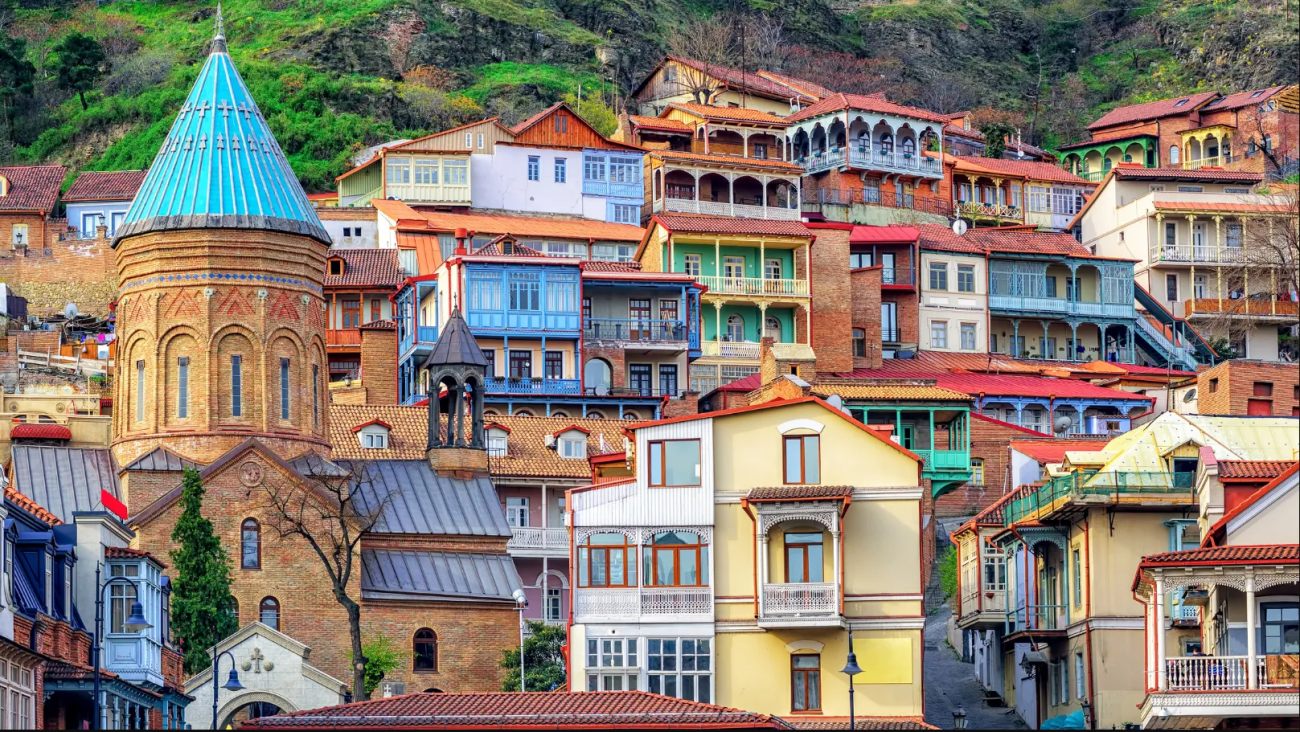 The colorful wooden balconied houses and a domed church tower in Tbilisi Old Town, stacked up a hillside