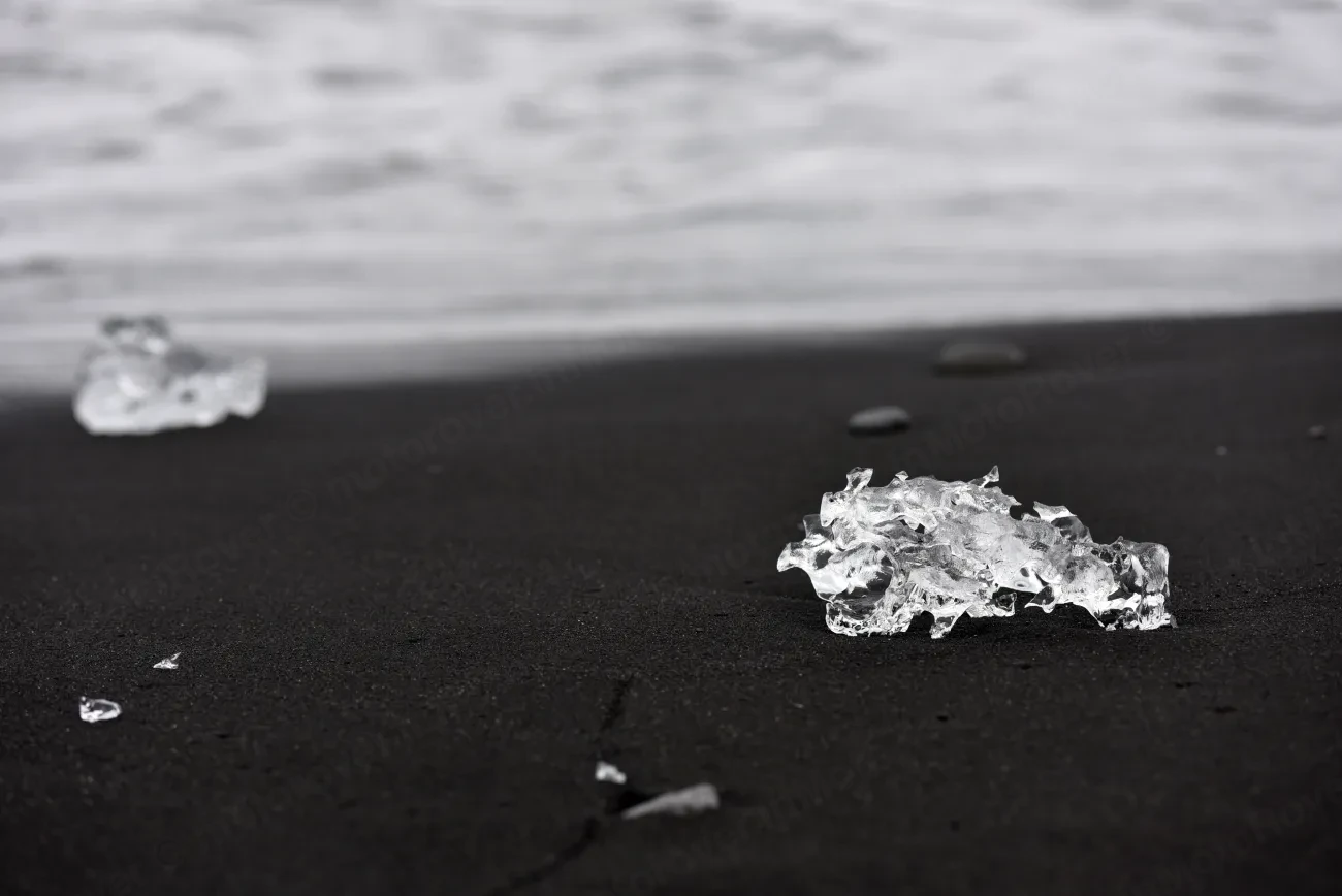 Clear blocks of glacier ice resting on the black volcanic sand of Diamond Beach