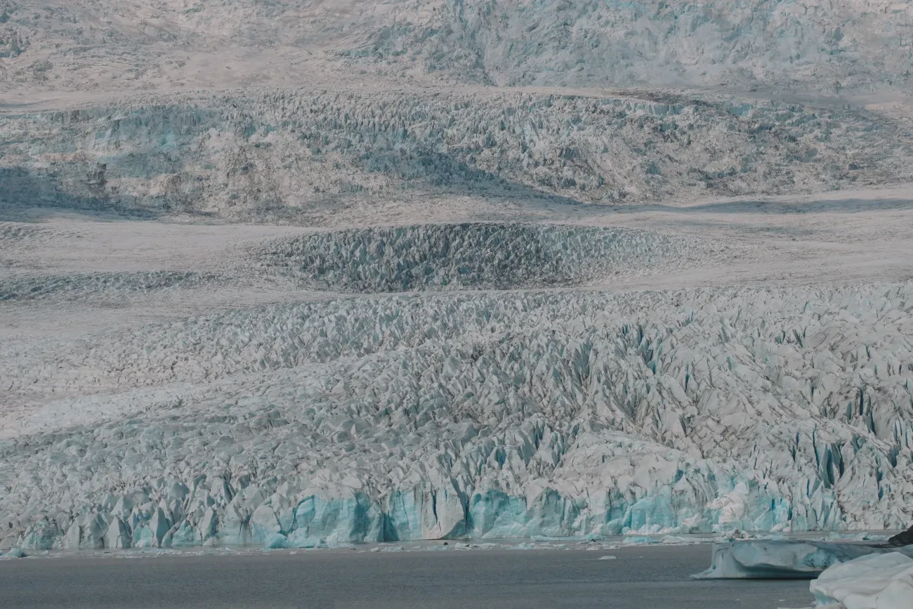 The crevassed face of an Icelandic glacier meeting its meltwater lagoon
