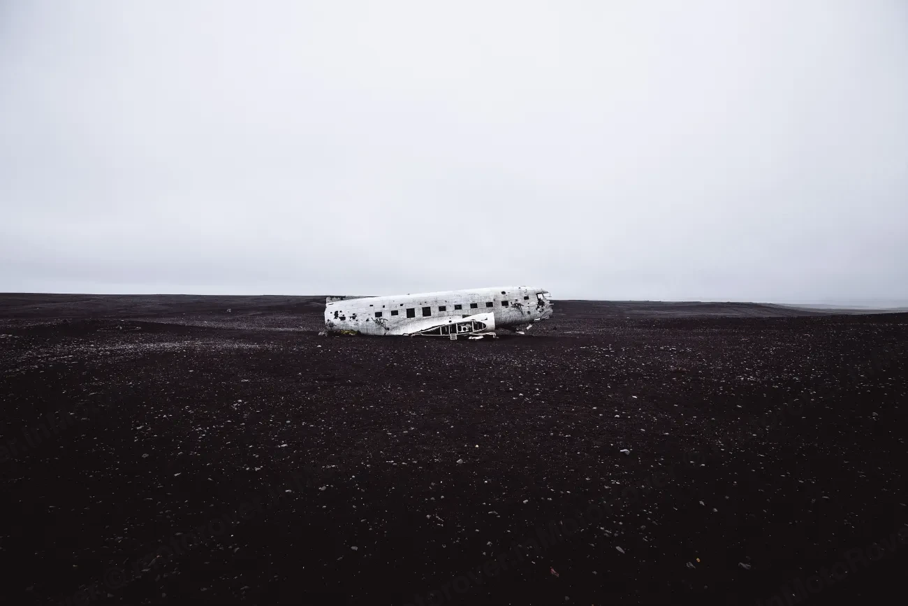 An abandoned aircraft fuselage on a vast black sand plain in Iceland