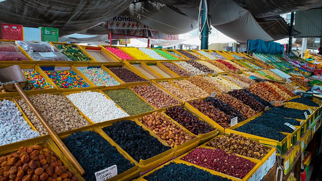 Colorful stalls of dried fruits, nuts, and sweets at a traditional Kyrgyz bazaar.