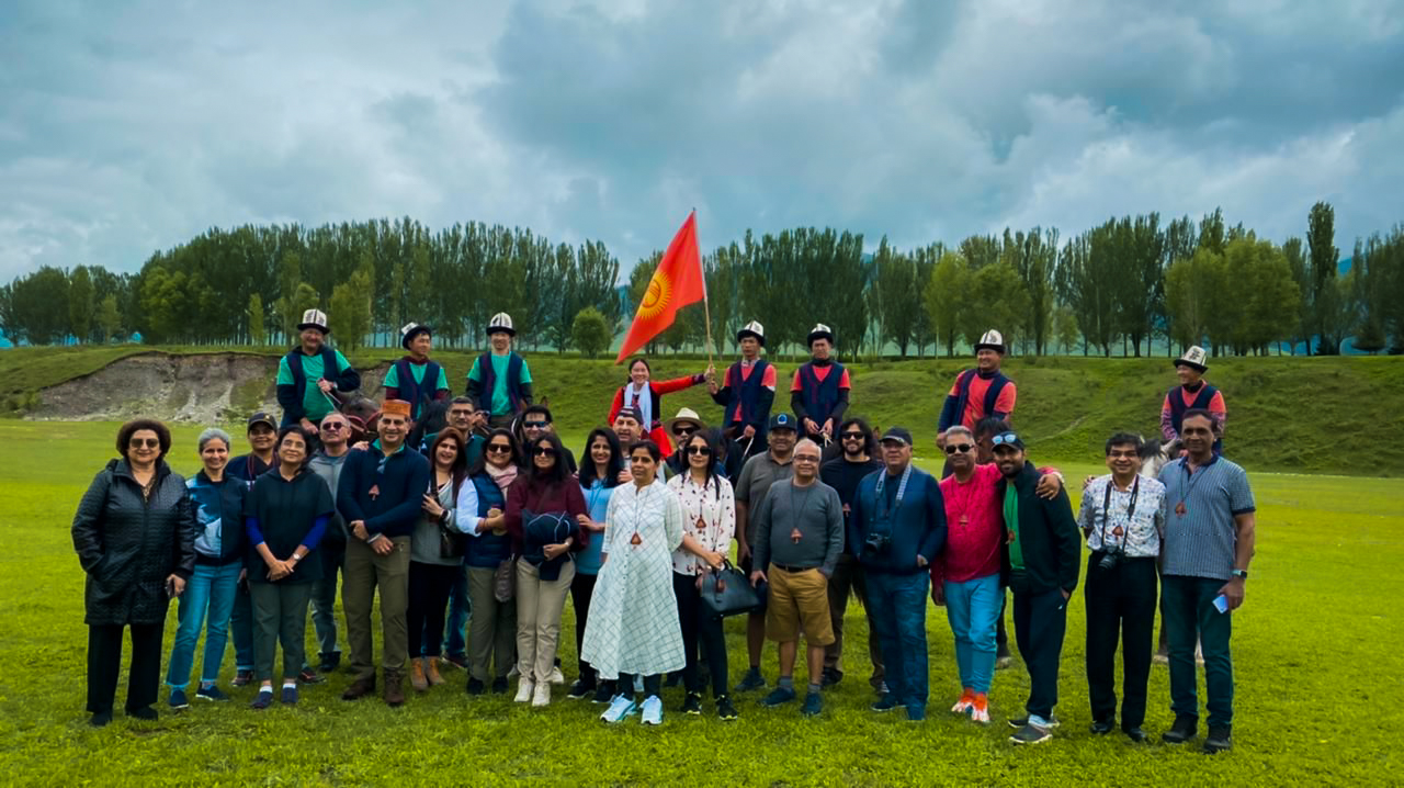MotoRover tour group with Kyrgyz flag on green meadow