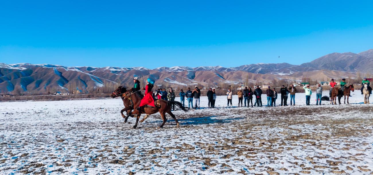 Kyrgyz horsemen playing the traditional kok-boru game on a snowy field with spectators watching
