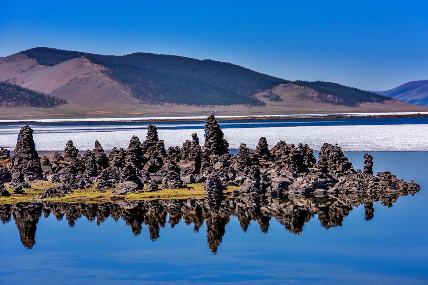 Stone cairns rising from the still blue waters of Terkhiin Tsagaan Lake in central Mongolia