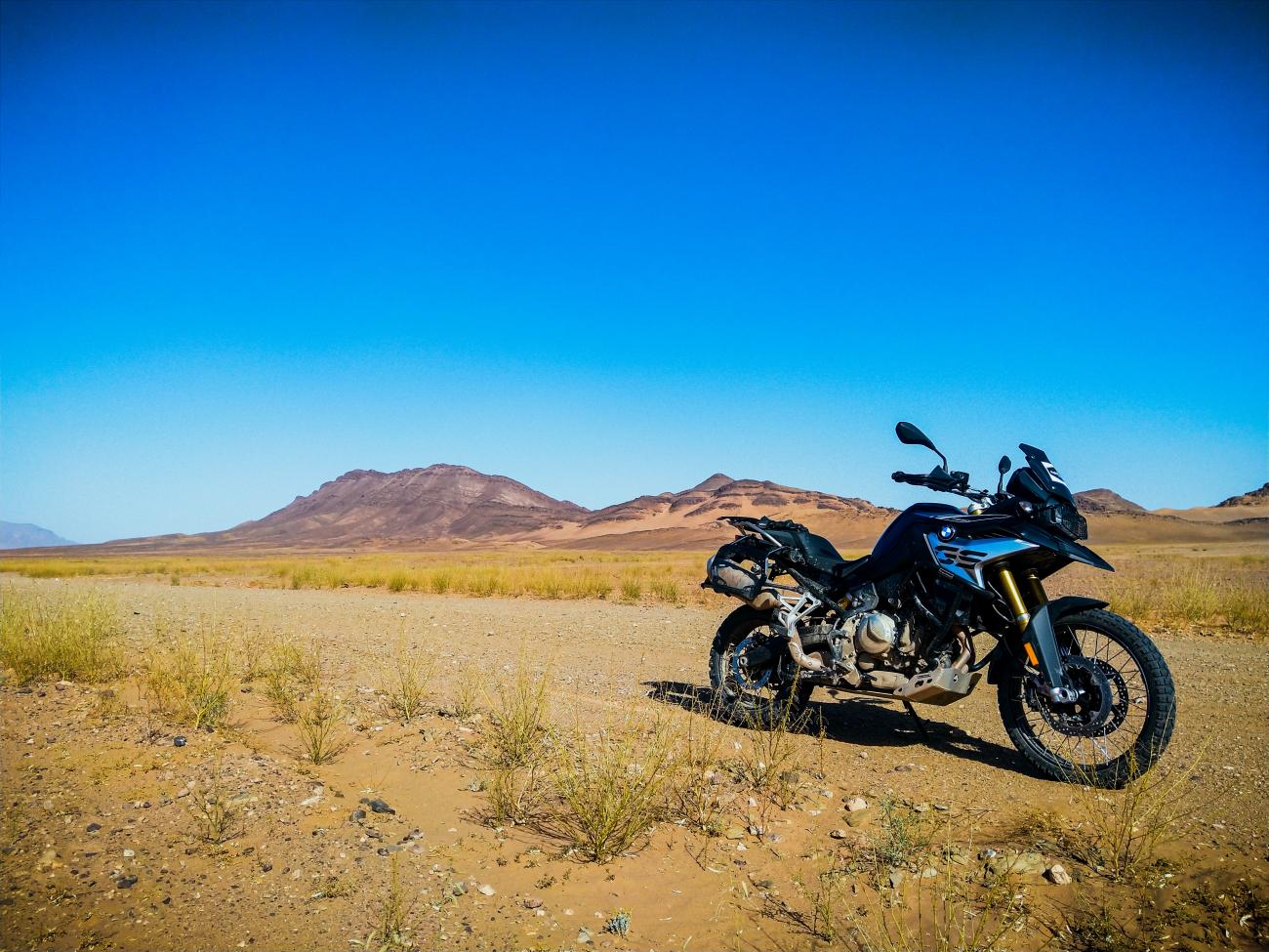 A BMW F 850 GS parked in the Moroccan desert with arid mountains in the background.