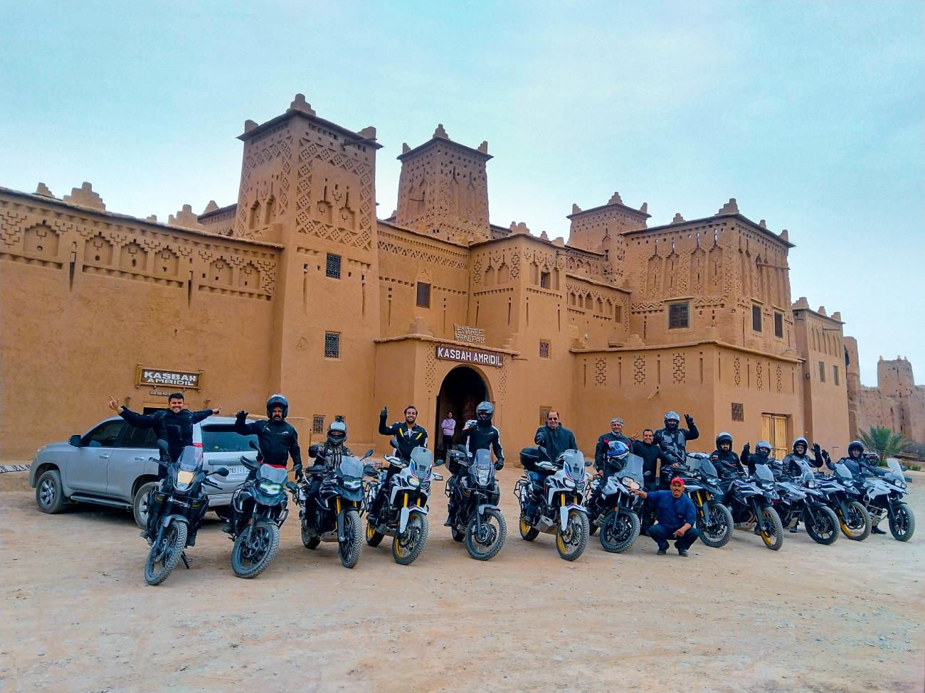 Riders gathered with their motorcycles in front of the historic Kasbah Amridil in Morocco.