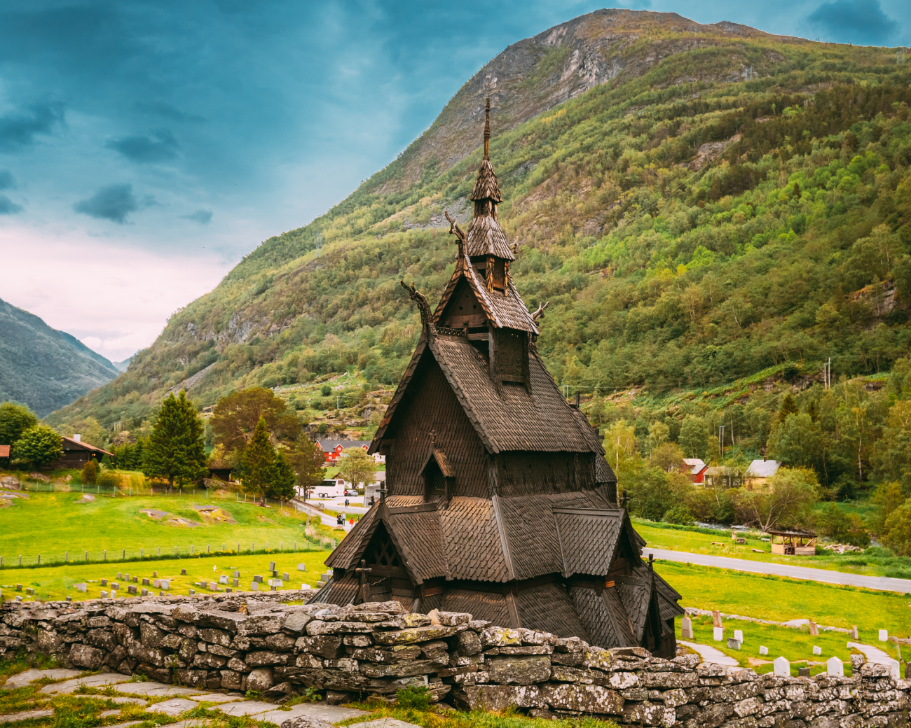 Historic Borgund stave church set against lush green mountains in a Norwegian valley.