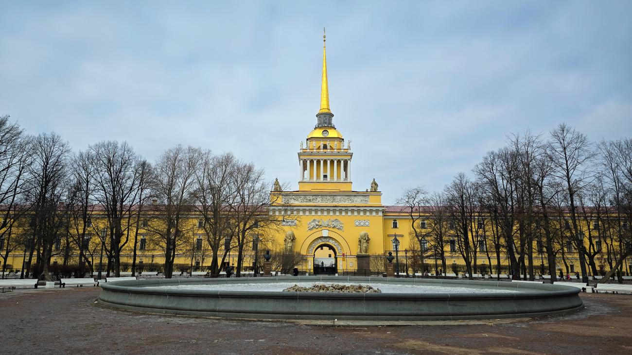The golden-spired Admiralty building in St Petersburg surrounded by bare winter trees and a light dusting of snow.