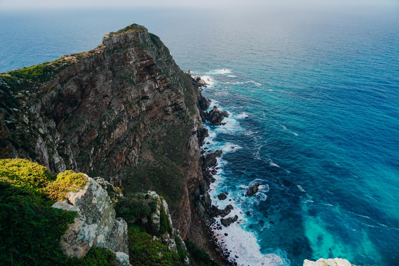 Dramatic rocky cliffs of Cape Point dropping into turquoise Atlantic Ocean waters.