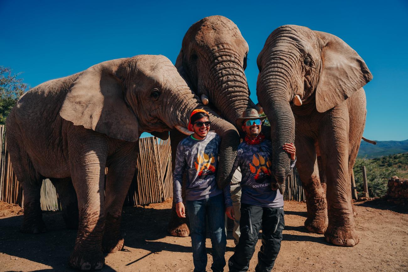 Two tour participants posing with African elephants at a wildlife sanctuary in South Africa.