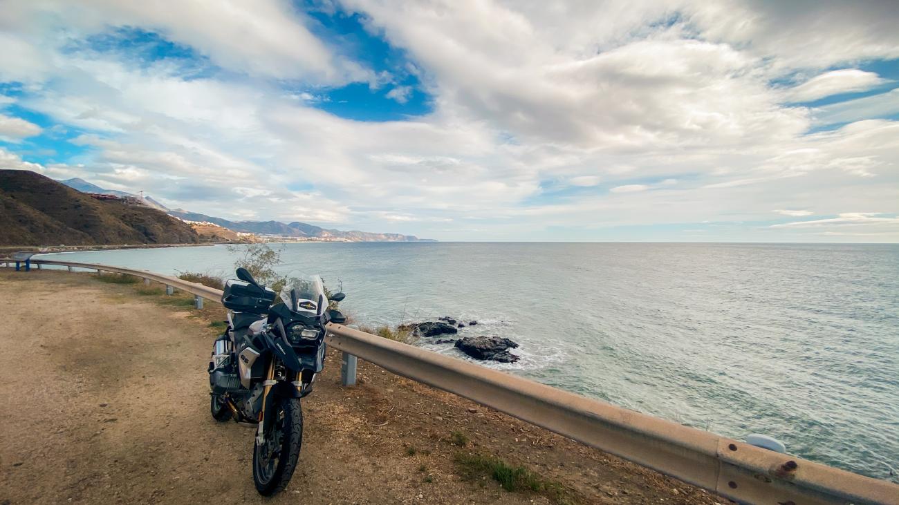 BMW adventure motorcycle parked at a coastal overlook on the Mediterranean coast of southern Spain.