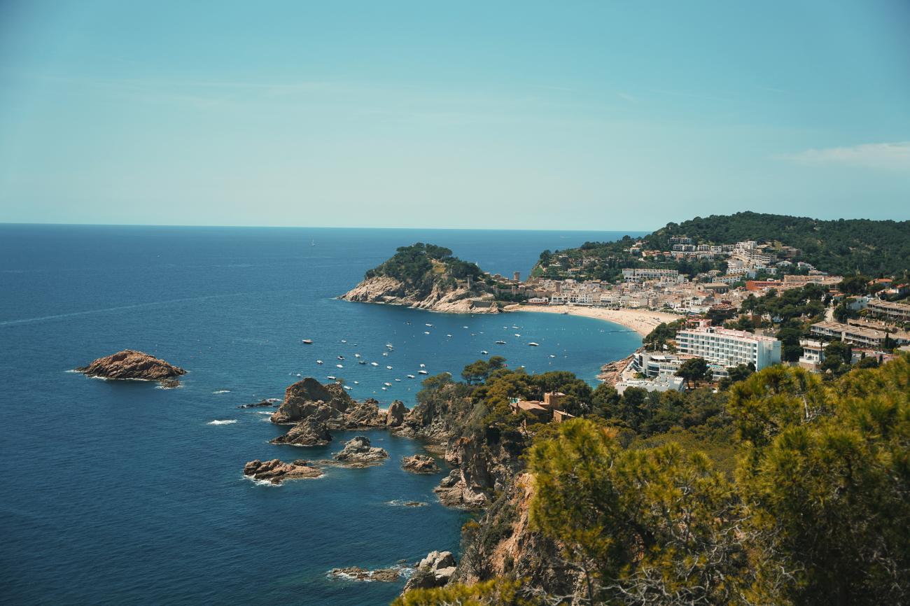 Panoramic view of the rocky Costa Brava coastline and Tossa de Mar town with turquoise Mediterranean waters.